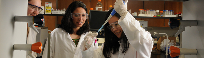 Two people in white coats working in a lab
