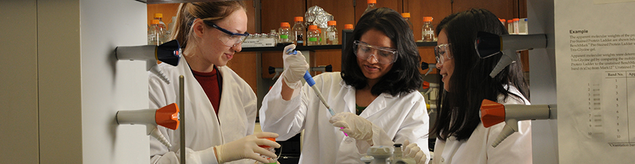 Two people in white coats working in a lab